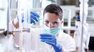 Wissenschaftlerin gießt eine Chemikalie in einen Messzylinder.