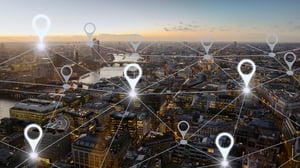 Luftaufnahme einer Stadt mit digital vernetzten Standortmarkierungen als Symbol für die zentrale Steuerung mehrerer Unternehmensstandorte..