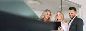 3 Personen im Büro schauen auf ein Tablet