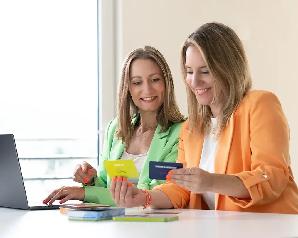 2 Personen sitzen lächelnd am Arbeitsplatz 2 Personen sitzen lächelnd am Arbeitsplatz
