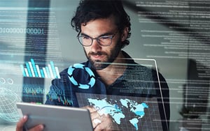 Person hält ein Tablet, im Hintergrund ist eine technische Grafik eingeblendet