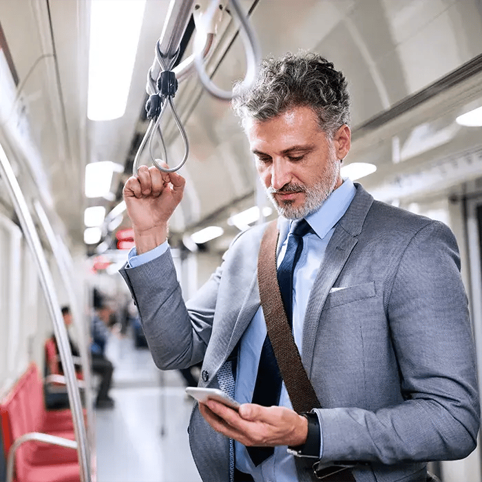 Mann nutzt barrierefreie Eticor Software mobil auf dem Smartphone in der Bahn Mann nutzt barrierefreie Eticor Software mobil auf dem Smartphone in der Bahn