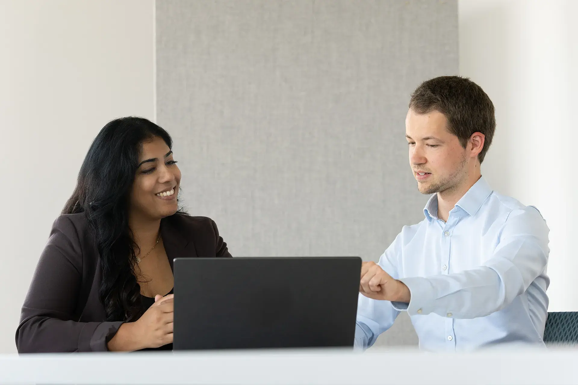 Two people talking in front of a laptop at a conference table during an organizational audit.