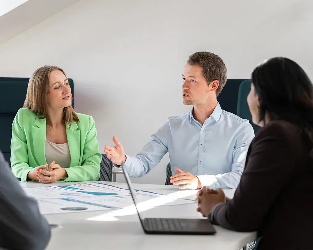Drei Personen im Gespräch an einem Besprechungstisch