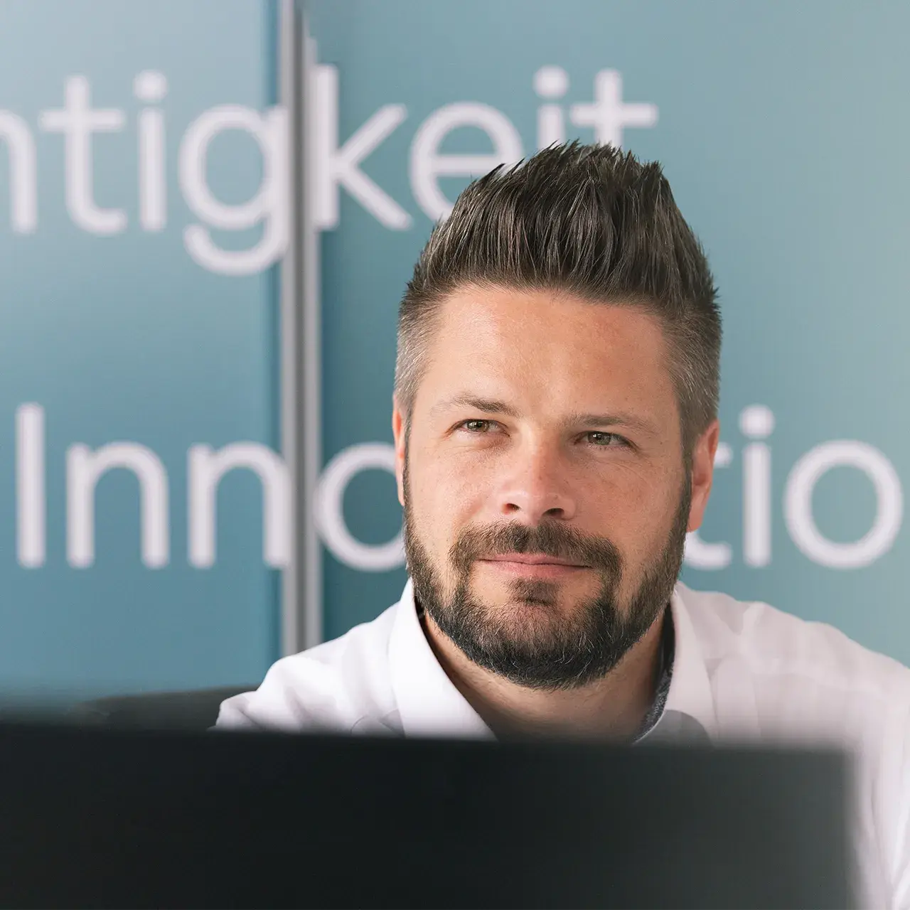 Ein Mitarbeitender sitzt am Rechner und blickt in die Ferne 